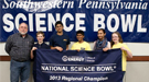 A group of students and teachers holding a banner that reads "National Science Bowl 2013 Regional Champion".