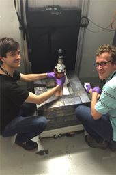 Bjorn Scholz (left) from the University of Chicago and Grayson Rich of the University of North Carolina at Chapel Hill and the Triangle Universities Nuclear Laboratory show off the world&rsquo;s smallest neutrino detector, which is part of the COHERENT experiment.