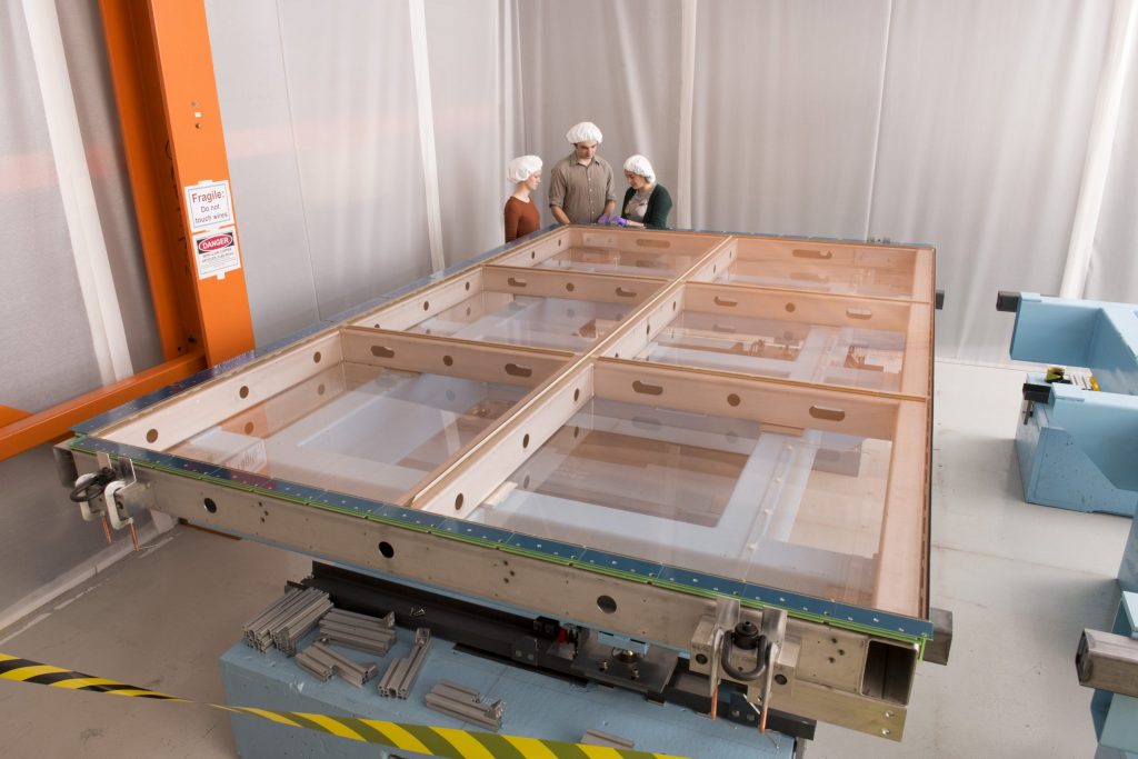 SBND collaborators Rhiannon Jones (left), Tom Brooks and Nicola McConkey discuss installation of one of the APAs. Photo: Reidar Hahn