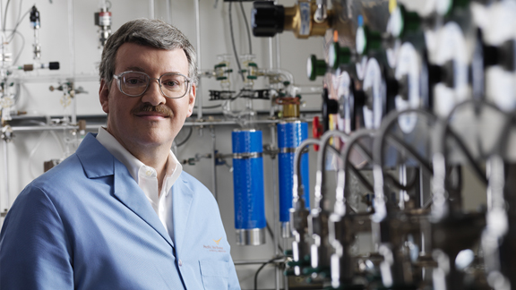 Scientist R. Morris Bullock standing in a laboratory with lab equipment in the background.